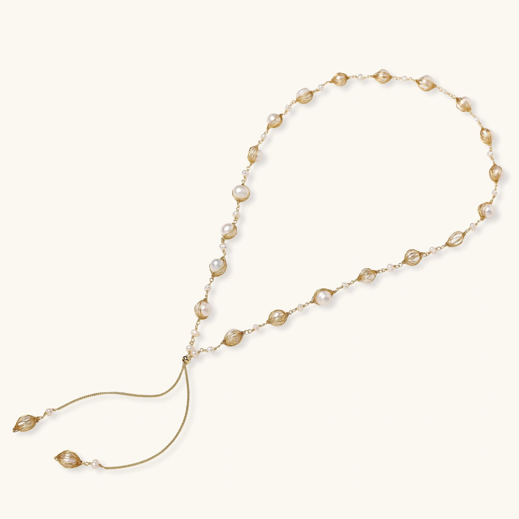 Adjustable gold lariat necklace with freshwater pearls nested in delicate cage settings and Y-shaped tassel drop