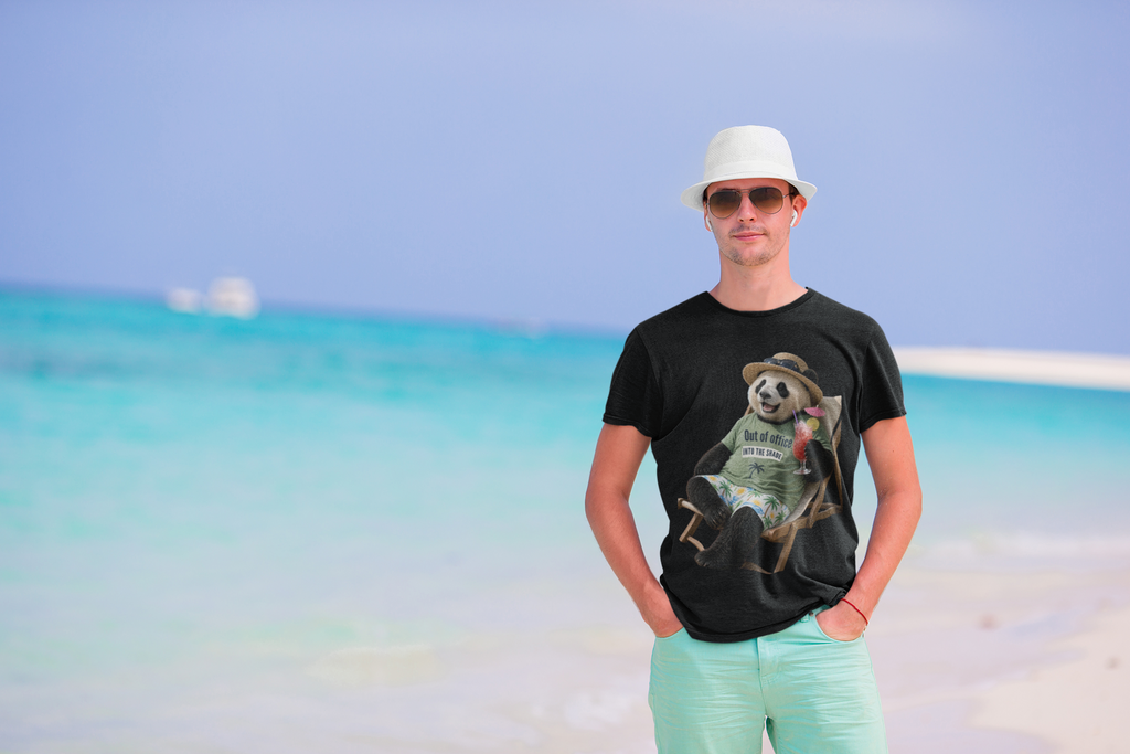 Man on a beach wearing a white graphic tee featuring a panda relaxing in a deck chair with a drink.