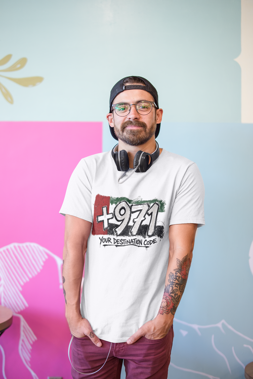 Man seated in a café wearing a white T-shirt with a +971 Your Destination Code graphic.
