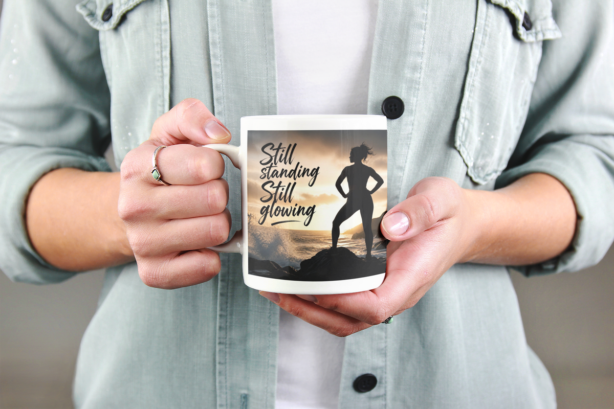 Still Standing Still Glowing - White mug held by woman in denim jacket