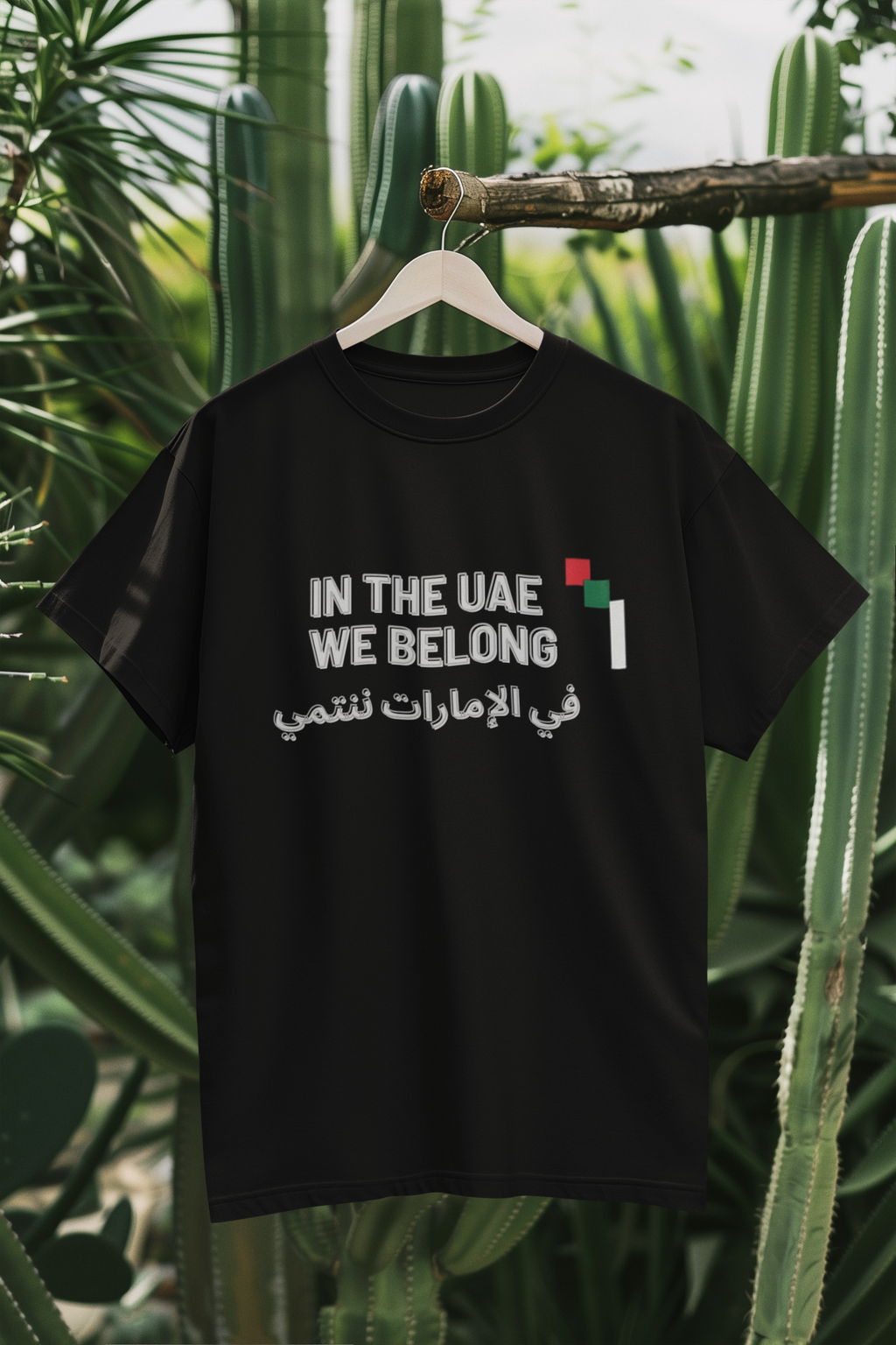 In the UAE We Belong black tee hanging on branch mockup
