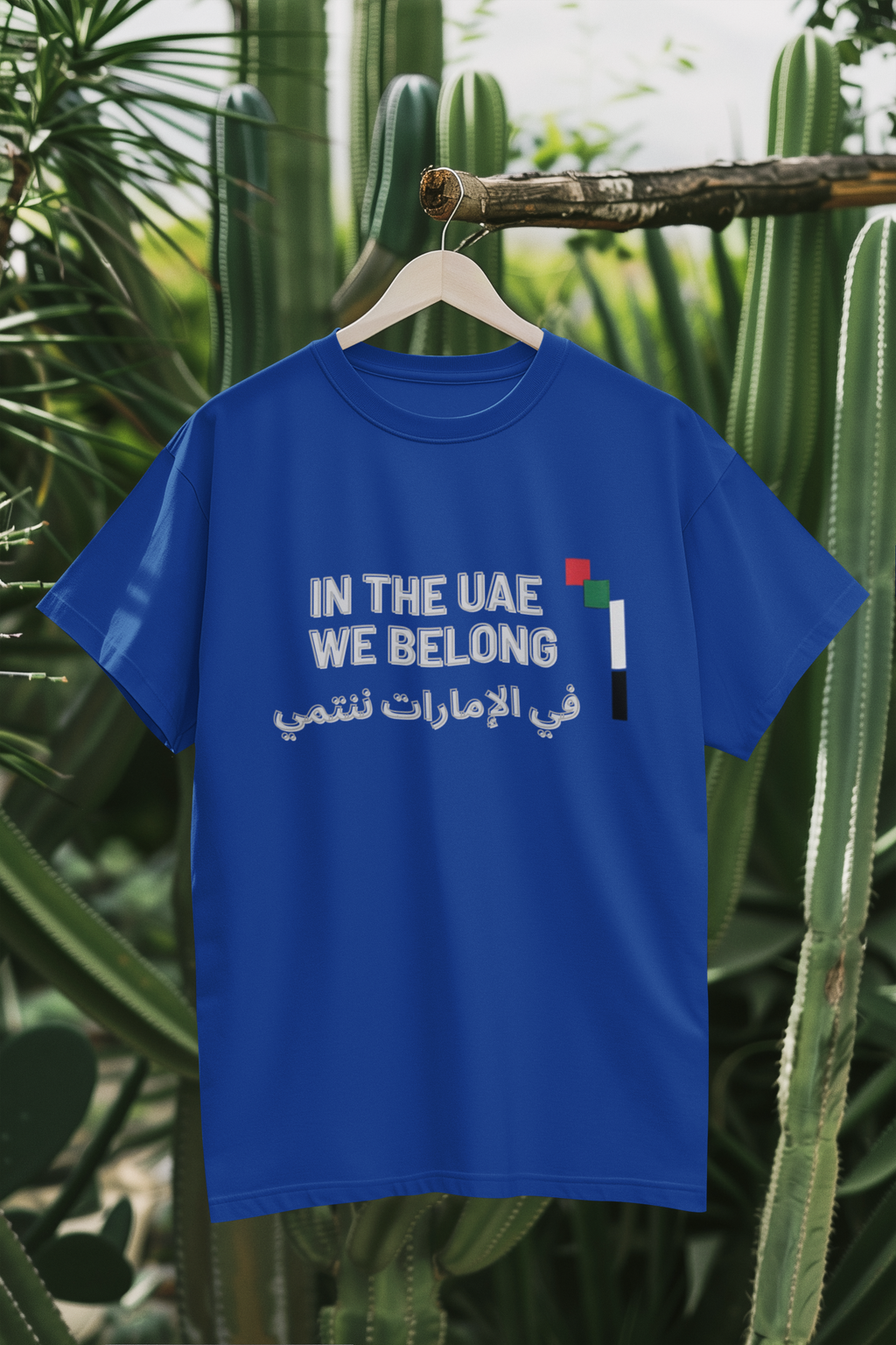 In the UAE We Belong blue tee hanging on branch mockup