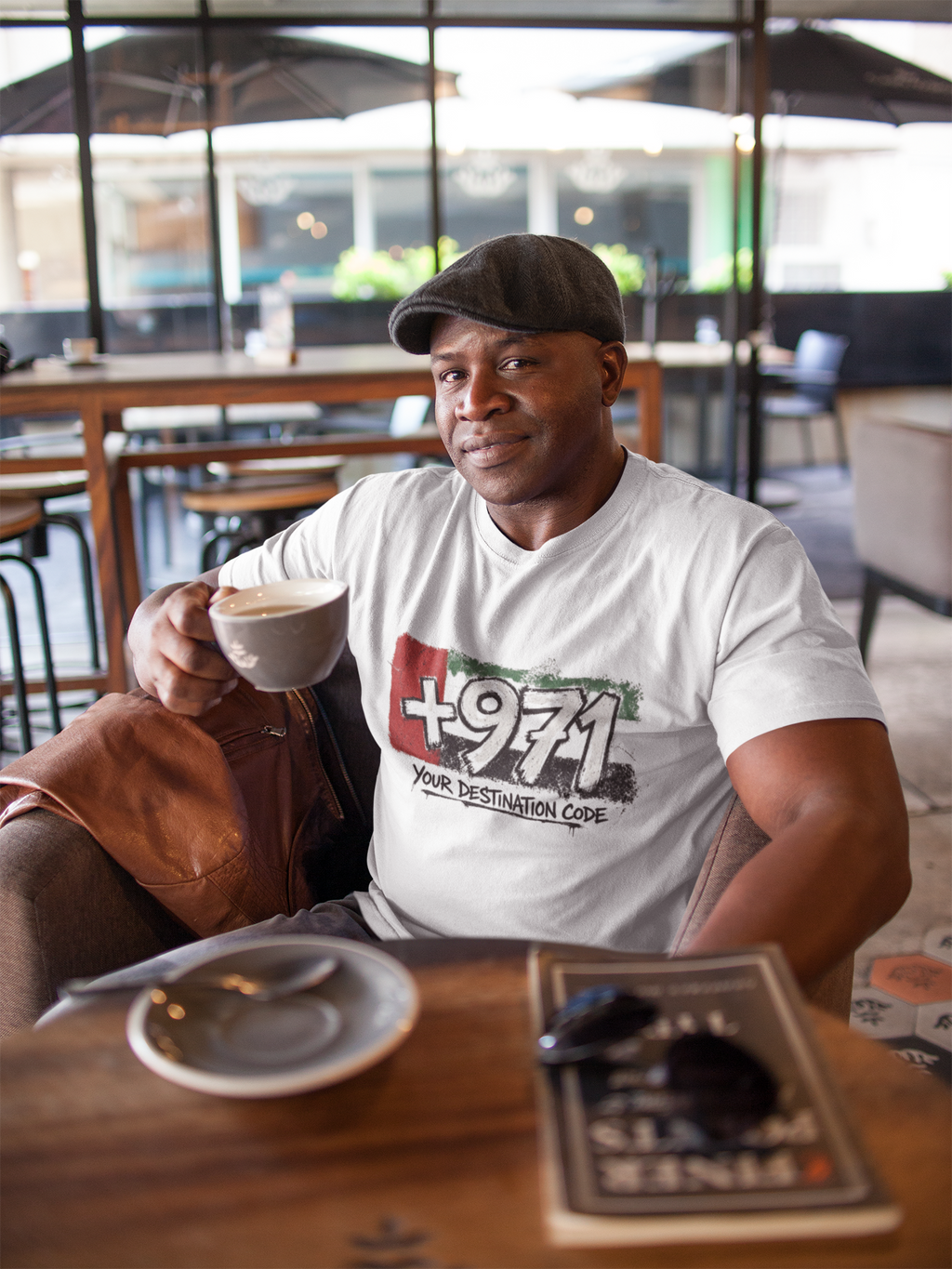 Man in a cap wearing a white +971 Your Destination Code graphic tee.